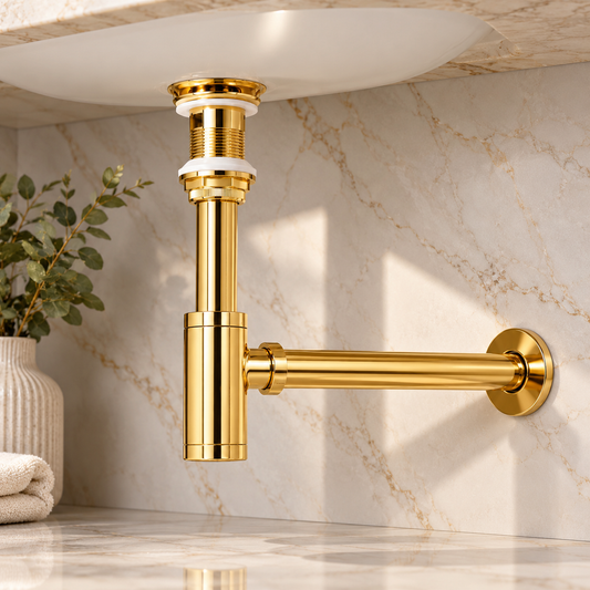 A polished gold wall-mounted sink drain assembly with a horizontal arm and pop-up drain component, shown installed beneath a white sink on a marble-look countertop and backsplash.