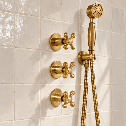 Close-up of Eden unlacquered brass handheld shower, flexible hose and three wall-mounted cross handles