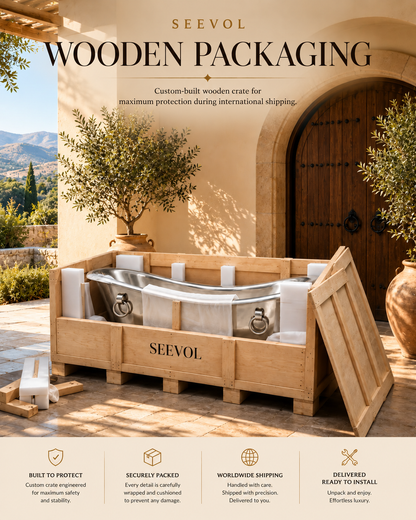 A custom-built wooden crate by SEEVOL, shown outdoors on a stone patio next to a large wooden door. The crate is filled with white protective foam inserts and a silver metal bathtub.