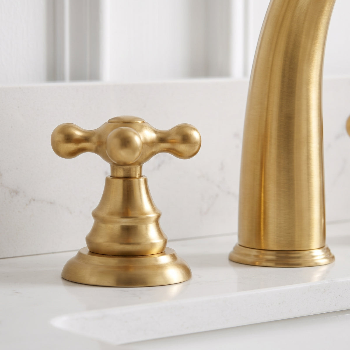 Close-up of the rounded cross handle and stepped base beside the unlacquered brass faucet spout