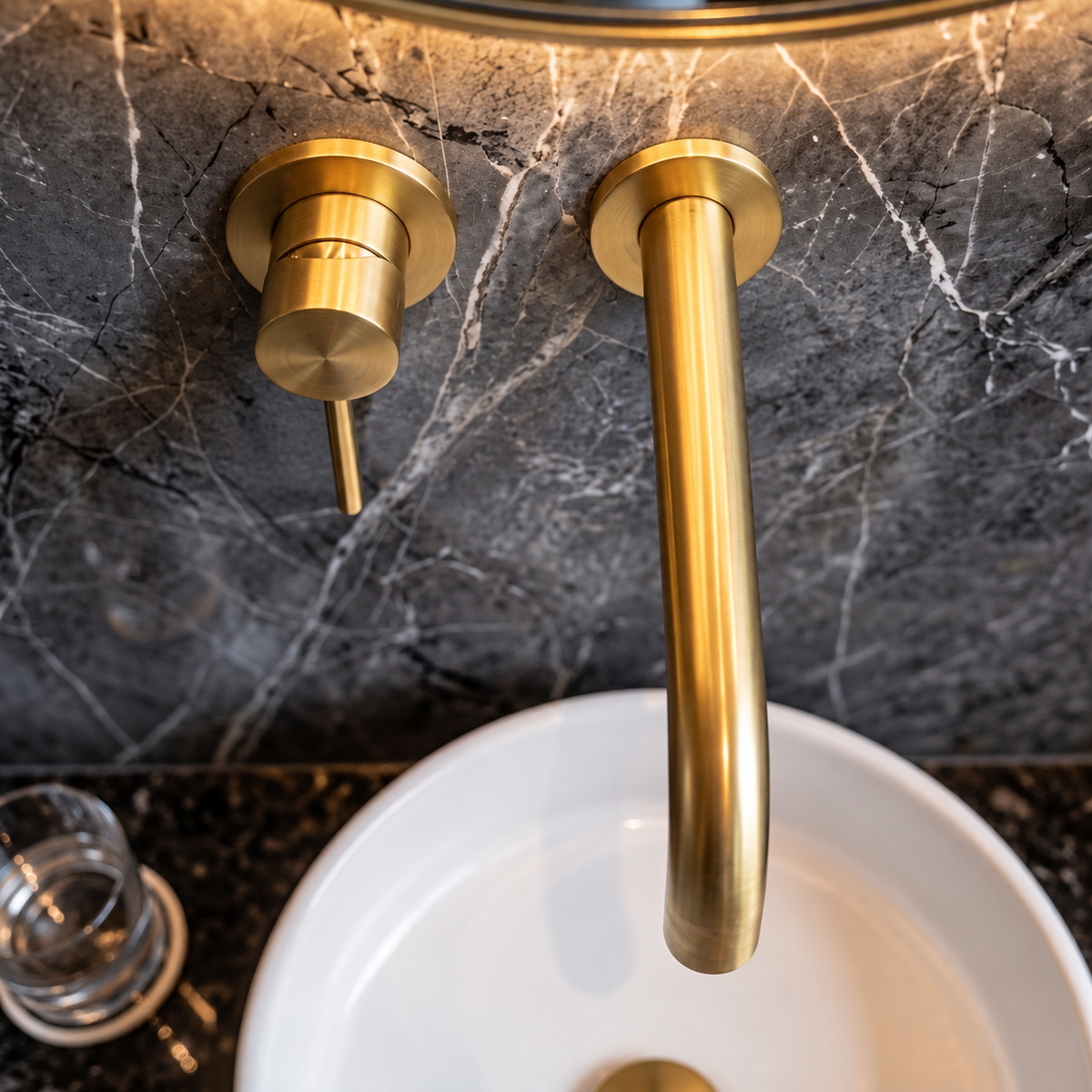 Overhead close-up of the unlacquered brass faucet’s curved spout and single lever above a white basin