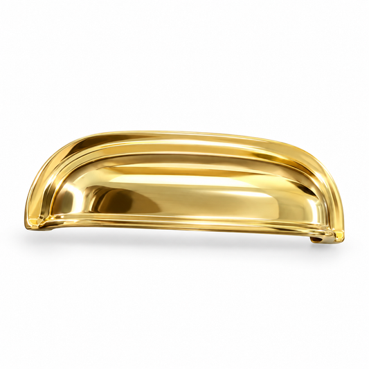 Solid unlacquered brass cabinet cup pull with a polished curved shell and stepped border on a white background