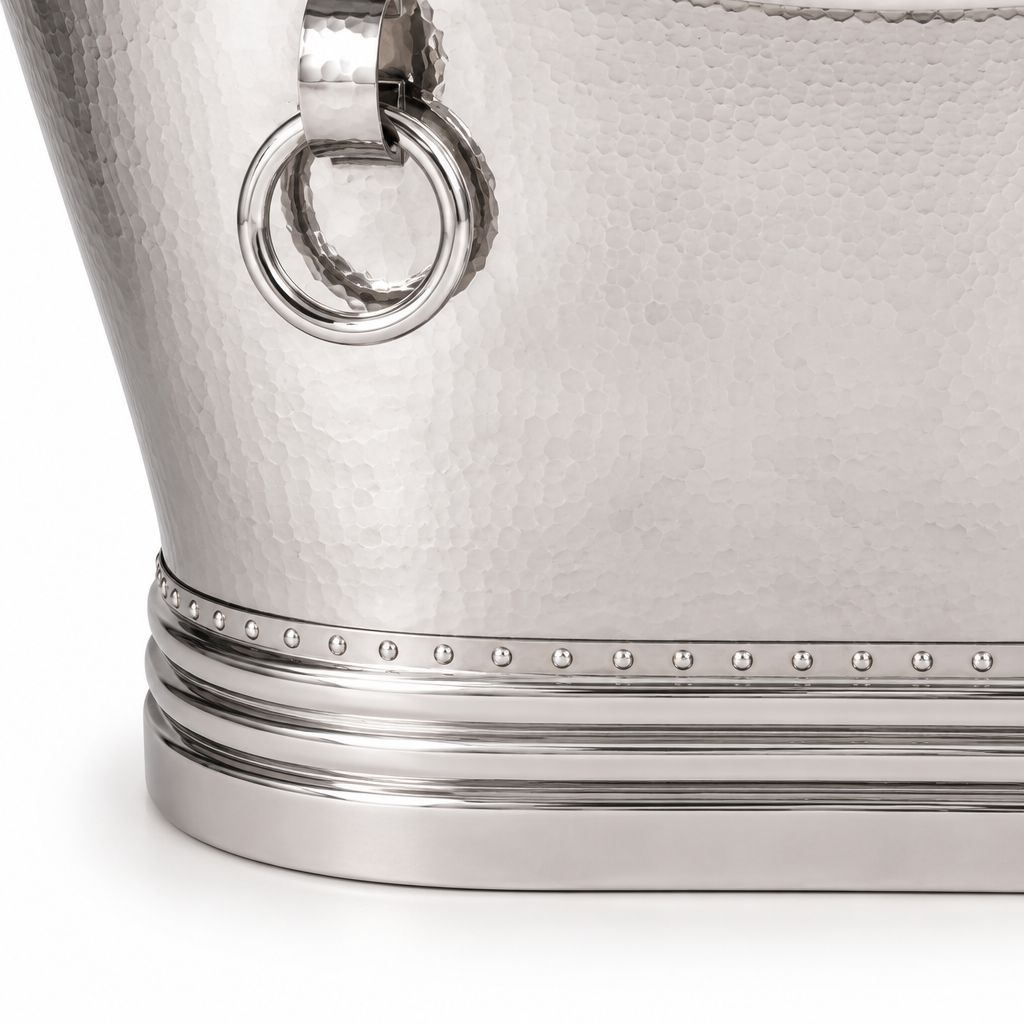 Close-up of a hammered silver metal bucket with a polished silver ring handle and decorative beaded band near the base, photographed on a white background.