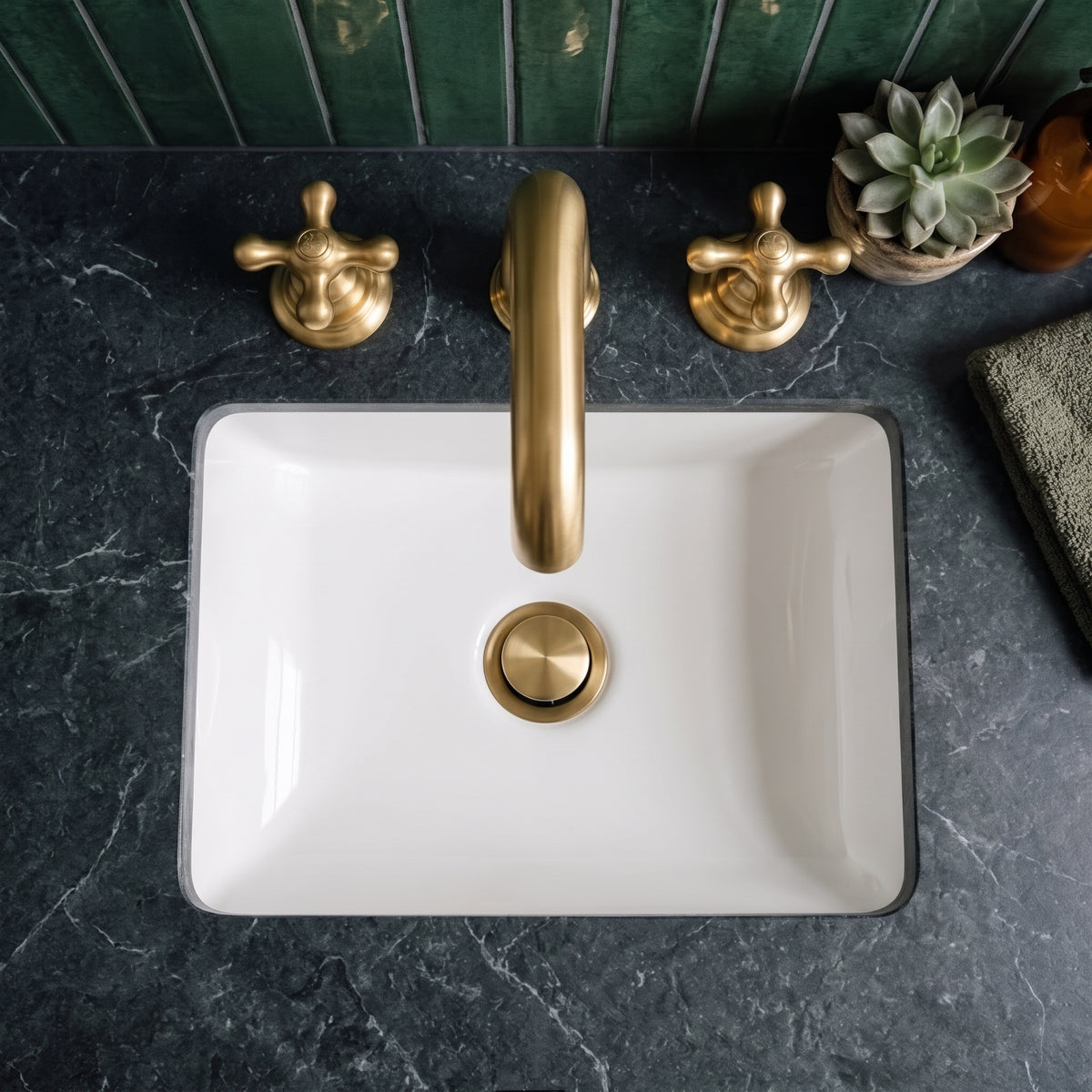 Overhead view of the widespread bathroom faucet above a white rectangular basin with a gold-toned drain